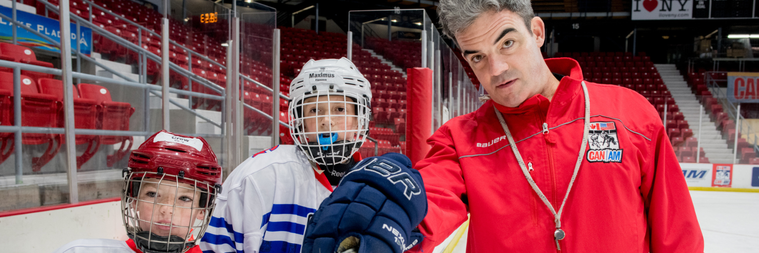 Coach with two campers pointing at area on the ice